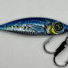 A Striper-Gear 3D Jigs metal fishing lures pictured in a blue metallic color is pictured on its side to show off its reflective properties and realistic color